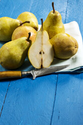 Williams pears and knife on blue wooden table - MAEF007414