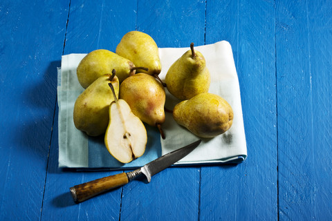 Williamsbirnen und Messer auf blauem Holztisch, lizenzfreies Stockfoto