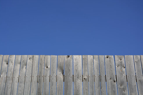 Grauer langer Bretterzaun vor blauem Himmel - AXF000594