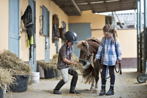 Deutschland, NRW, Korchenbroich, Junge und Mädchen im Reitstall mit Mini-Shetlandpony, lizenzfreies Stockfoto