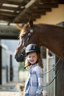 Germany, NRW, Korchenbroich, Little girl with horse in stable - CLPF000002