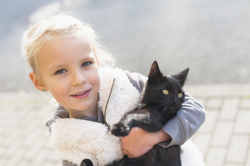 Porträt eines lächelnden kleinen Mädchens mit Katze im Arm, Nahaufnahme - MJF000424