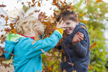 Two little boys throwing autumn leaves - MJF000435