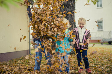 Three children throwing autumn leaves - MJF000421