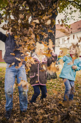 Three children throwing autumn leaves - MJF000415