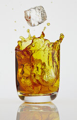 Ice cube splashing into glass of Whiskey - AKF000268