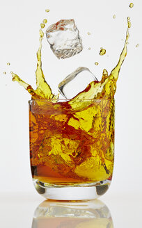 Eiswürfel spritzt in ein Glas Whiskey - AKF000269