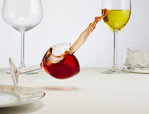 Glass of red wine toppling down on table stock photo