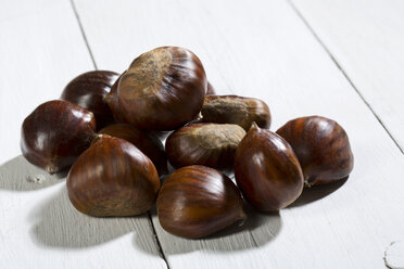 Esskastanien (Castanea sativa) auf weißem Holztisch - MAEF007473