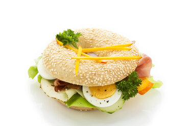 Sesame seed bagel garnished with slices of bacon, lettuce, cucumber, carrot, egg, Fol Epi and parsley - MAEF007488