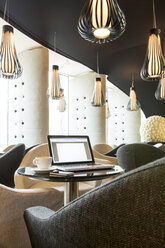 Polen, Warschau, Laptop, Smartphone und Kaffeetasse in der Lounge eines Hotels - MLF000234