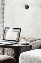 Polen, Warschau, Laptop und Kaffeetasse im Aufenthaltsraum eines Hotels - MLF000240