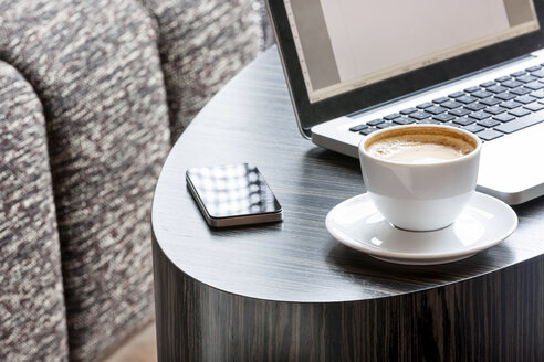 Polen, Warschau, Laptop, Smartphone und Kaffeetasse in der Lounge eines Hotels - MLF000247