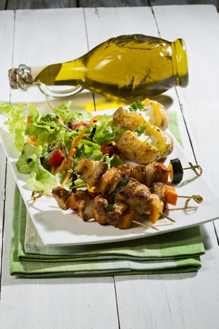 Hähnchenfleischspieße mit Ofenkartoffeln und gemischtem Salat, lizenzfreies Stockfoto