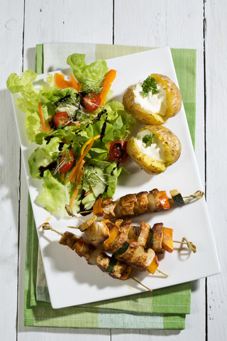 Hähnchenfleischspieße mit Ofenkartoffeln und gemischtem Salat, lizenzfreies Stockfoto