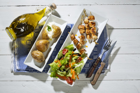 Hähnchenfleischspieße mit Ofenkartoffeln und gemischtem Salat, lizenzfreies Stockfoto