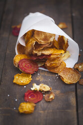 Roasted vegetable chips made of parsnips, sweet potatoes, beetroots, carrots and turnips on wooden table - ECF000396