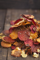 Roasted vegetable chips made of parsnips, sweet potatoes, beetroots, carrots and turnips on wooden table - ECF000398