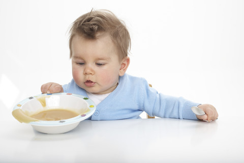 Kleiner Junge verschüttet Brei, Studioaufnahme, lizenzfreies Stockfoto