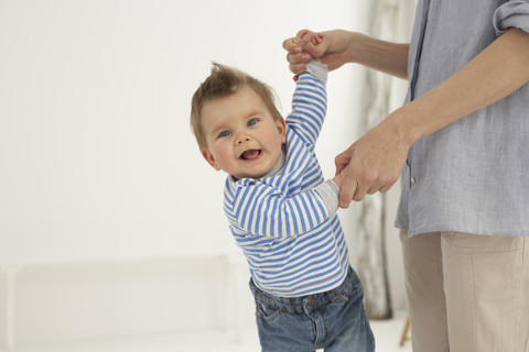 Smiling baby boy hand in hand with his mother stock photo