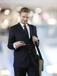 Businessman with sling bag using smart phone - STKF000703