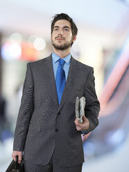 Portrait of businessman with briefcase and newspaper - STKF000707