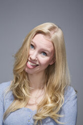Porträt einer jungen Frau mit herausgestreckter Zunge - MAEF007545