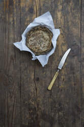 Tomme de Savoie cheese on greaseproof paper, knife on wooden table - LVF000354