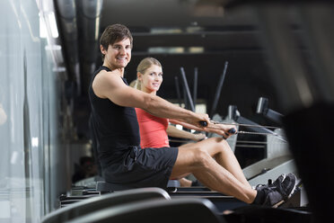 Austria, Klagenfurt, Man and woman exercising with rowing machine - DAWF000029