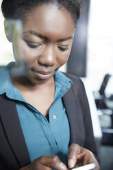 Germany, Neuss, Young Afro-european business woman using smart phone - STKF000865