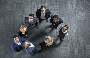 Germany, Neuss, Business people standing on floor, looking up - STKF000771