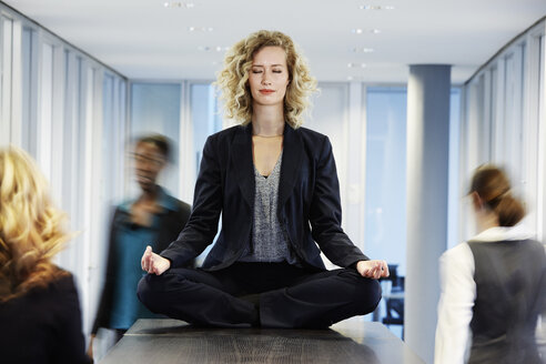 Germany, Neuss, Business woman meditating on desk - STKF000755