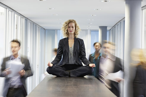 Germany, Neuss, Business woman meditating on desk - STKF000754