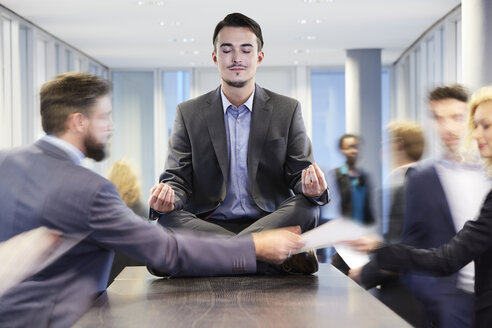 Germany, Neuss, Business man meditating on desk - STKF000748