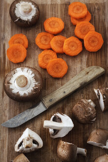 Holzbrett mit Küchenmesser, Karottenscheiben und Crimini-Pilzen - EVGF000274