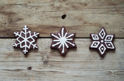 Three gingerbread stars decorated with sugar icing on wooden table stock photo