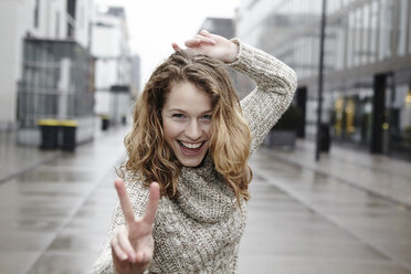 Portrait of happy young woman showing victory sign - FMKF000931