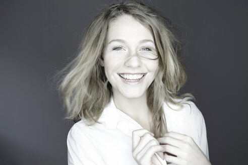 Porträt einer lächelnden jungen Frau, Studioaufnahme - FMKF000940