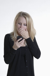 Schockierte junge Frau schaut auf ihr Smartphone - CRF002524
