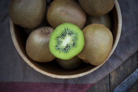 Schale mit Kiwis (Actinidia deliciosa) auf Holztisch, lizenzfreies Stockfoto