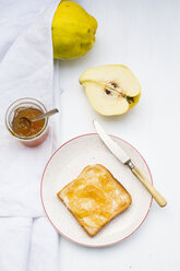 Quinces (Cydonia oblonga), selfmade quince jelly and slice of toast on white wooden table - LVF000375