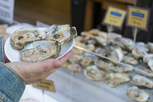 USA, California, San Francisco, Woman holding a paper plate with fresh raw oysters - ABA001089