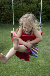 Concentrated ittle girl swinging in the garden - CRF002530