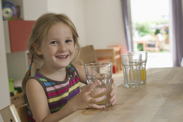 Smiling little girl sitting in the kitchen - CRF002528