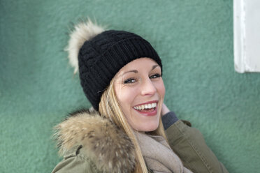 Porträt einer lächelnden jungen Frau vor einer grünen Wand - DRF000330
