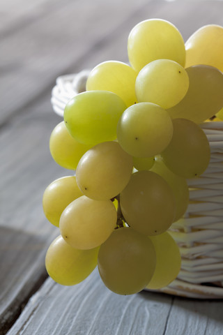 Grüne Weintrauben (Vitis vinifera) in weißem Korb, Nahaufnahme, lizenzfreies Stockfoto