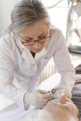 Heilpraktikerin gibt älterer Frau Injektionsakupunktur - TCF003738