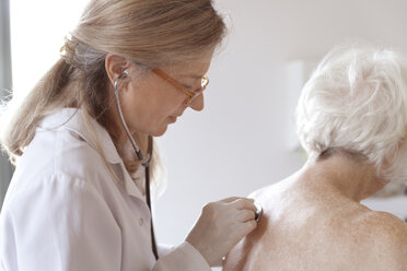 Heilpraktikerin auskultiert ältere Frau mit Stethoskop - TCF003755