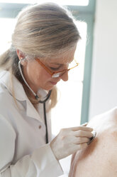 Female alternative practitioner auscultating senior woman with stethoscope - TCF003782