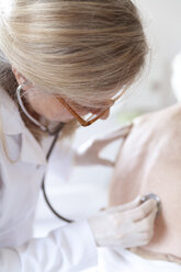 Female alternative practitioner auscultating senior woman with stethoscope - TCF003756